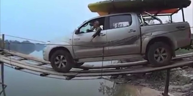 Truck attempting to go across a very thin wooden bridge